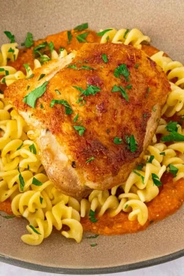 Chicken romesco pasta in a beige plate.