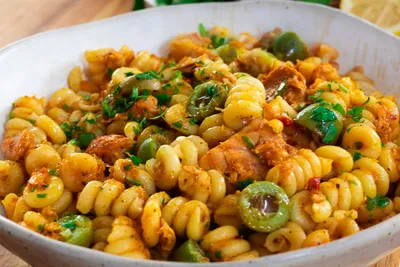 Delicious Creamy Calabrian Chili Tuna Pasta with olives, tuna, herbs, and spices in a white bowl.