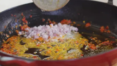 Chopped onions and peppers sizzling in hot oil in a pan.