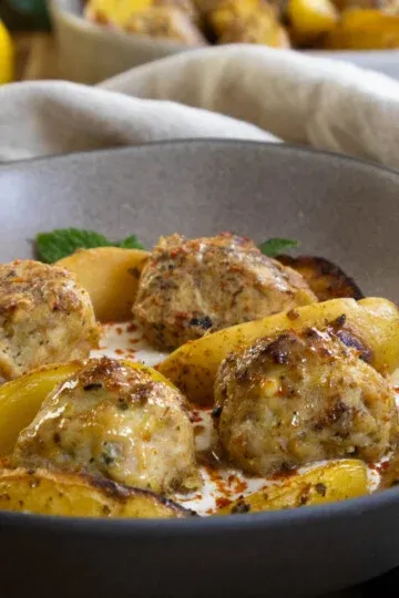 Hearty Greek feta chicken meatballs and roasted potatoes garnished in a bowl.