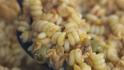 Close-up of delicious fusilli pasta with vegetables and spices in a pan.