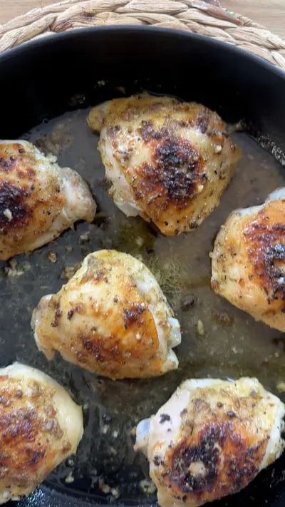 Roasted chicken thighs with crispy skin in a black skillet.