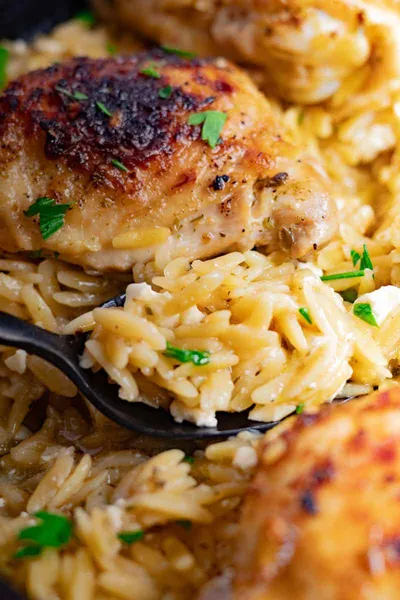 Greek Chicken Orzo Bake served over creamy orzo pasta garnished with fresh parsley.