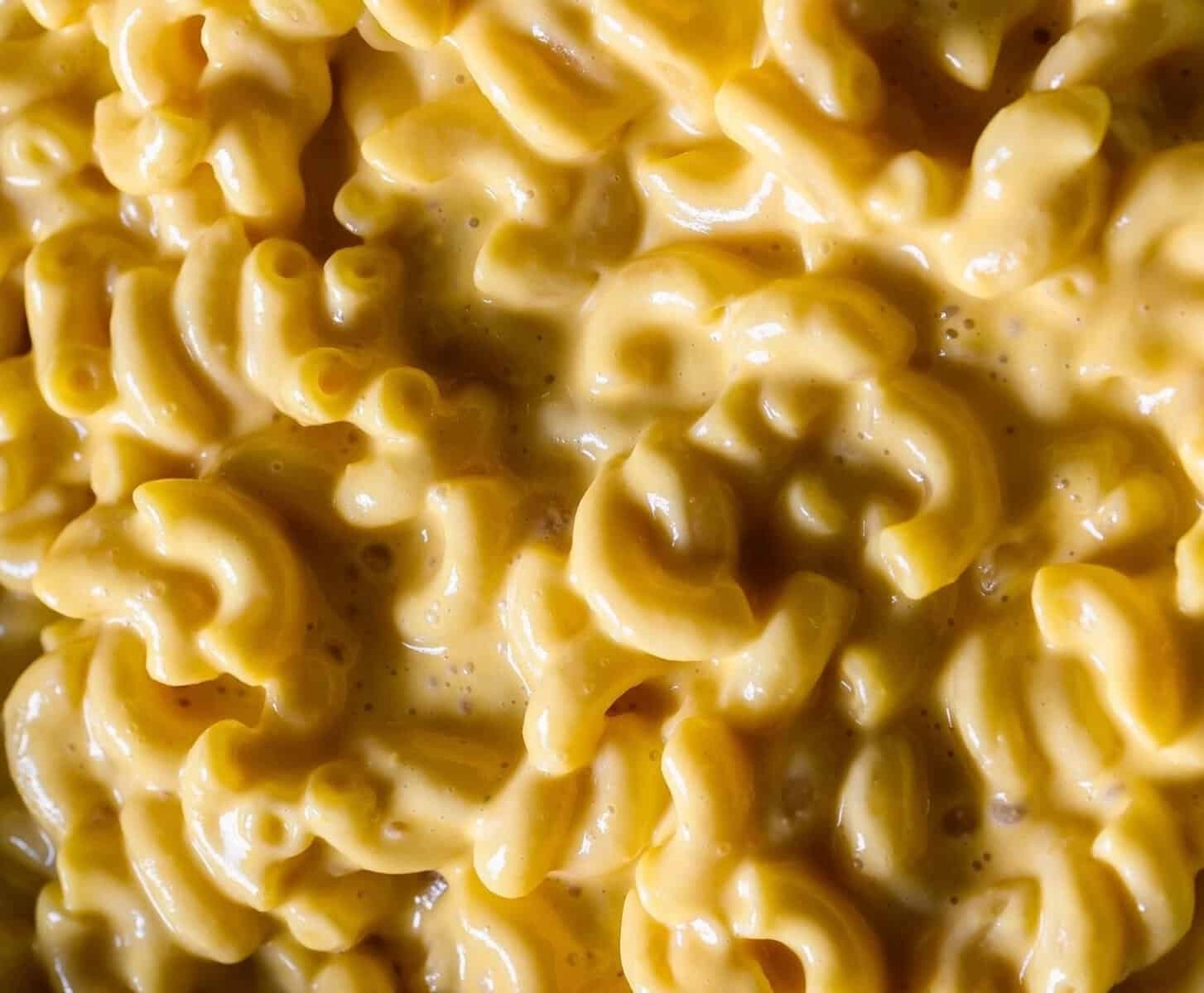 Creamy macaroni and cheese with rich, gooey cheddar sauce, capturing the classic comfort food close-up.