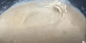 Creamy sauce being stirred in a skillet, seasoned with black pepper for a rich flavor.