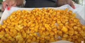 Tray of seasoned diced potatoes on parchment paper, ready for roasting.
