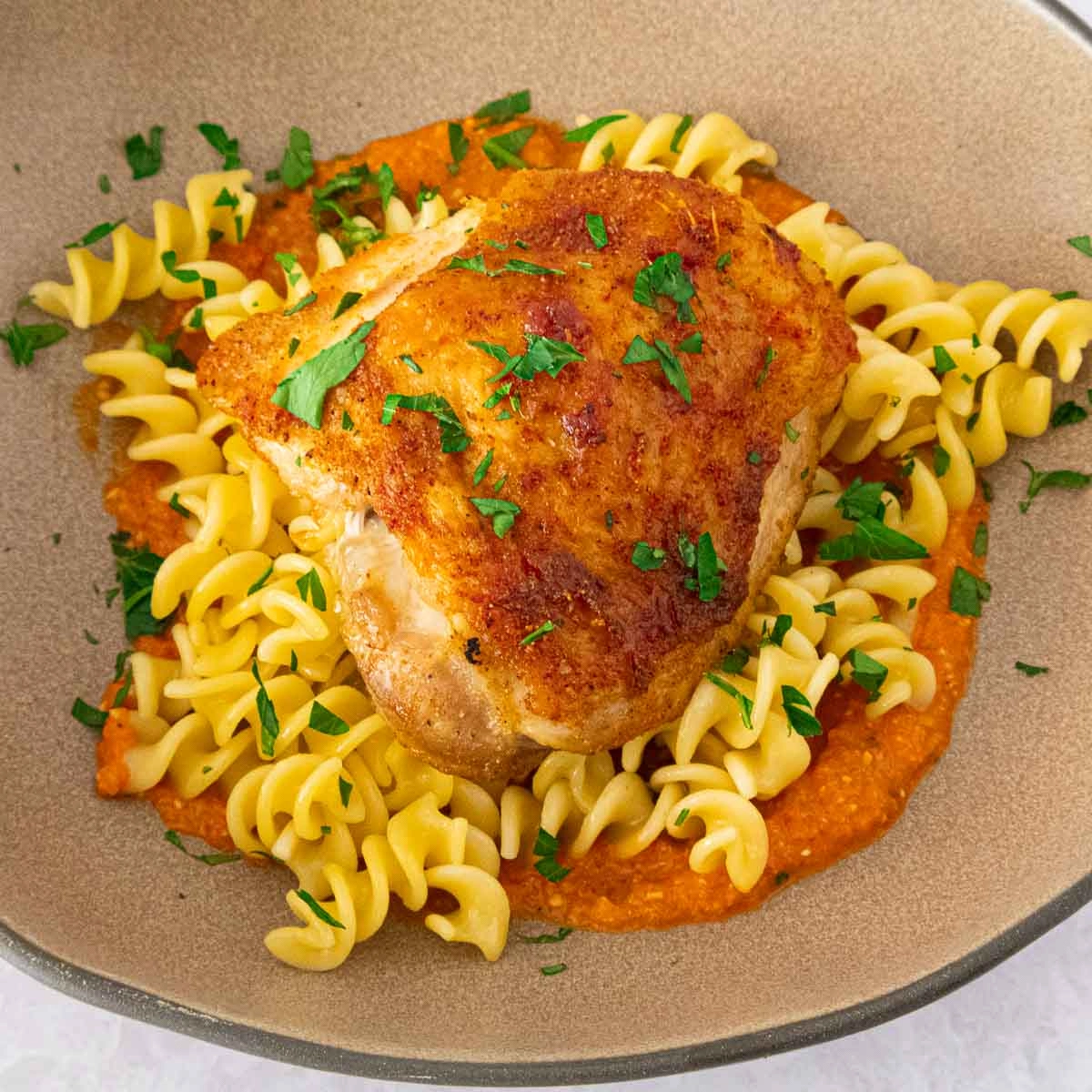 Chicken romesco pasta in a beige plate.
