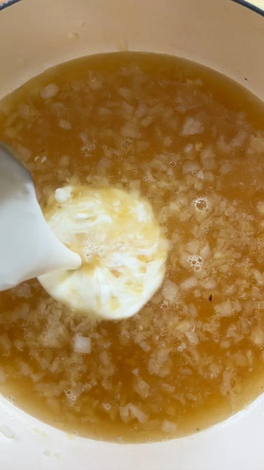 Adding cream in pot of liquids and diced onions.