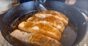 Pan-seared salmon fillets with seasoning in a cast iron skillet.