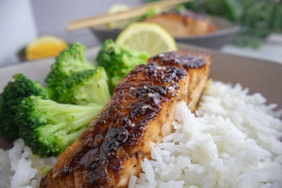 Grilled salmon with steamed broccoli and jasmine rice, garnished with lemon for a healthy meal.