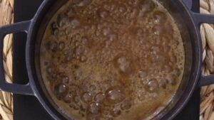 Boiling caramel in a black pot, creating a rich and bubbly texture for a delicious dessert topping.