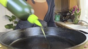 Pouring oil into a cast iron pan in a cozy kitchen setting.