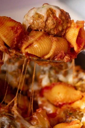 Cheesy baked meatball pasta in tomato sauce on a fork.