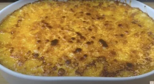Golden baked cheesy casserole with a crispy top layer in a white dish.