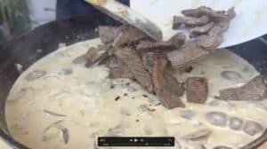 Cooking creamy beef stroganoff with mushrooms in a skillet.