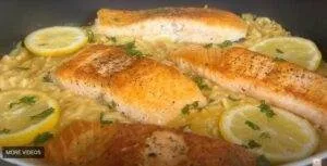 Grilled salmon on creamy orzo with lemon slices and parsley garnish.