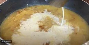 Cream being poured into a pot of simmering soup or stew, creating a swirl pattern.