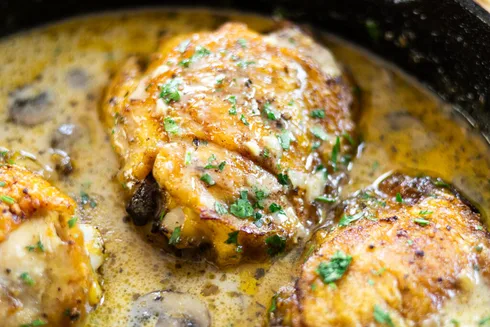 Creamy chicken and gravy with mushrooms in a skillet.